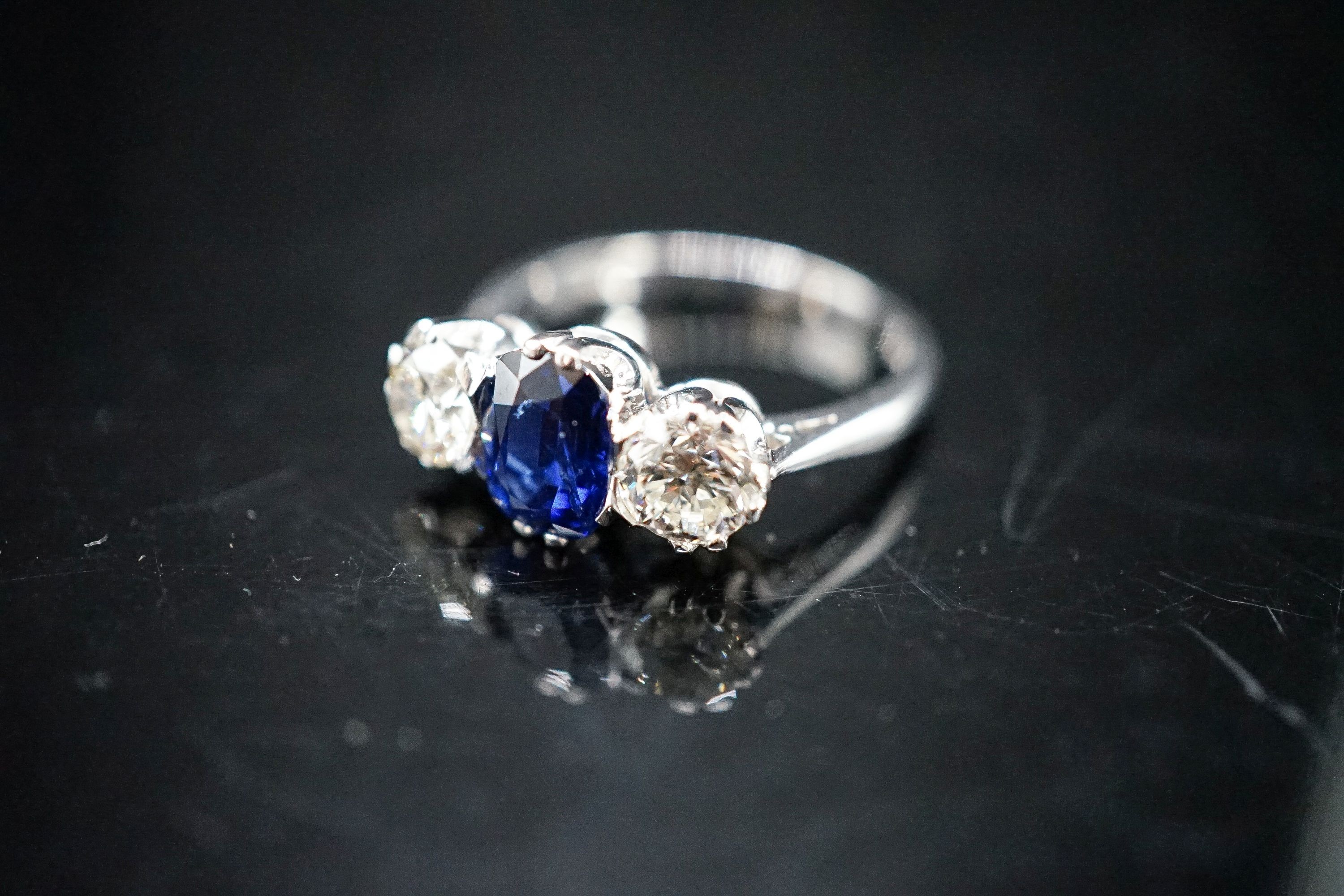 A modern 18ct white gold, single stone sapphire and two stone diamond set ring, size L, gross weight 4.2 grams